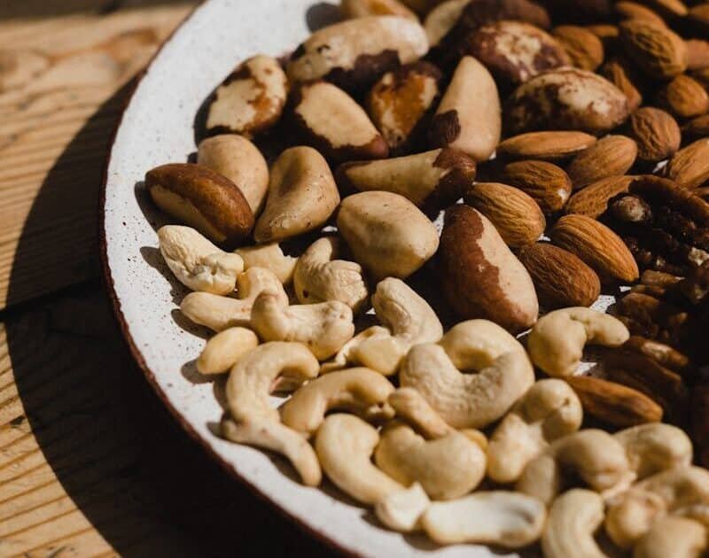 A close-up of various nuts on a ceramic plate, showcasing texture and natural light.