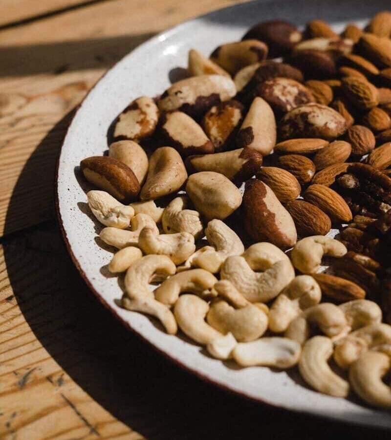 A close-up of various nuts on a ceramic plate, showcasing texture and natural light.