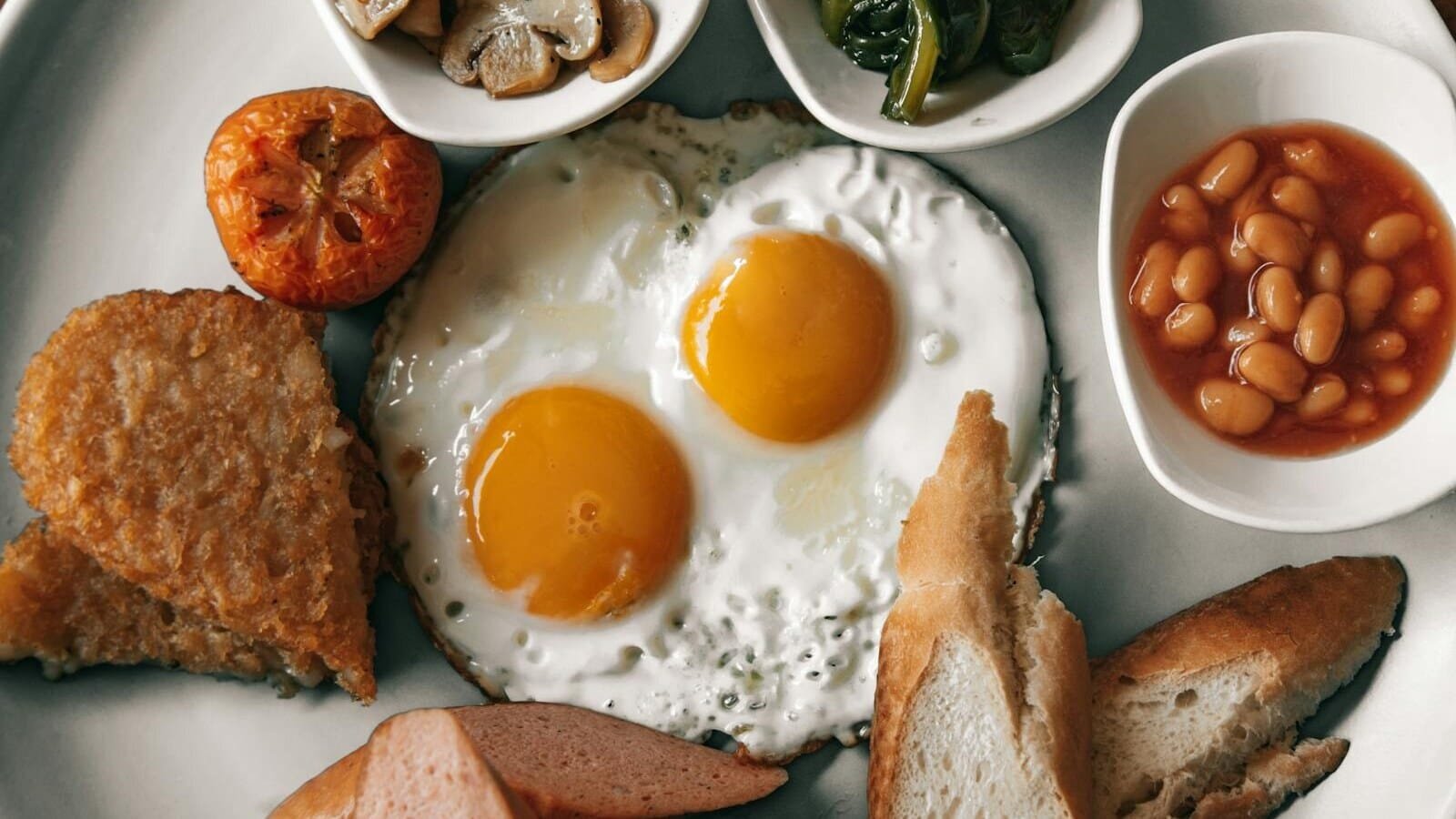 Delicious full English breakfast with fried eggs, toast, and baked beans on a plate.