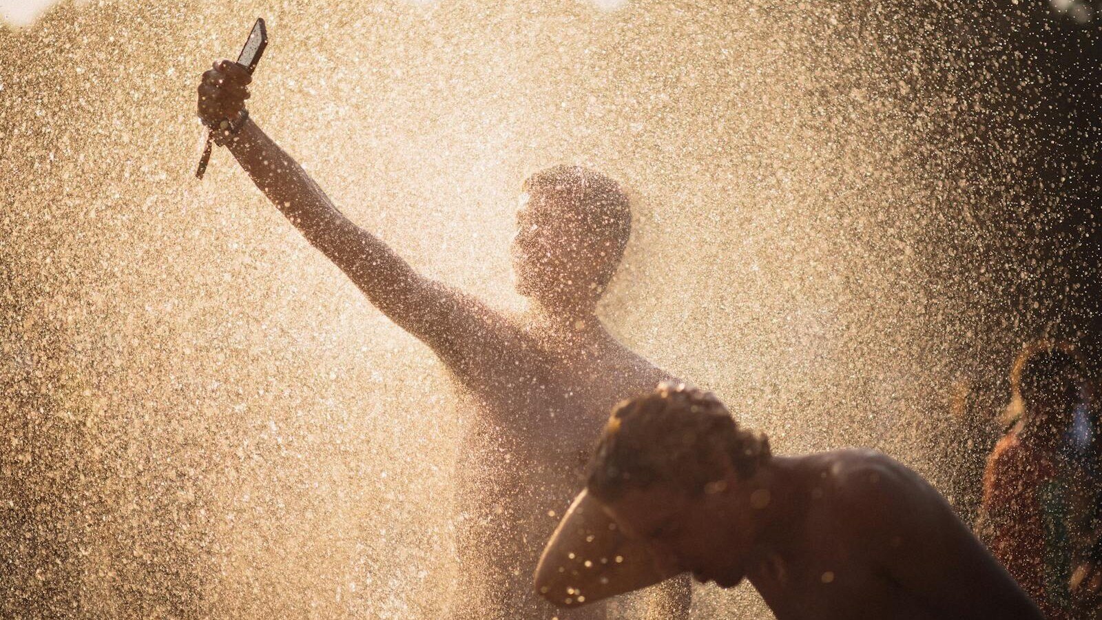 Men enjoying a refreshing water splash under the summer sun in Budapest.