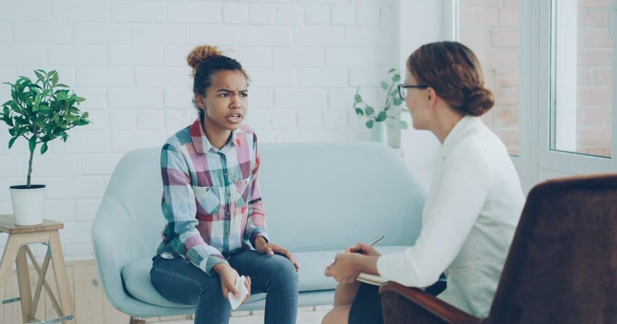 A woman talks to a therapist in an office.