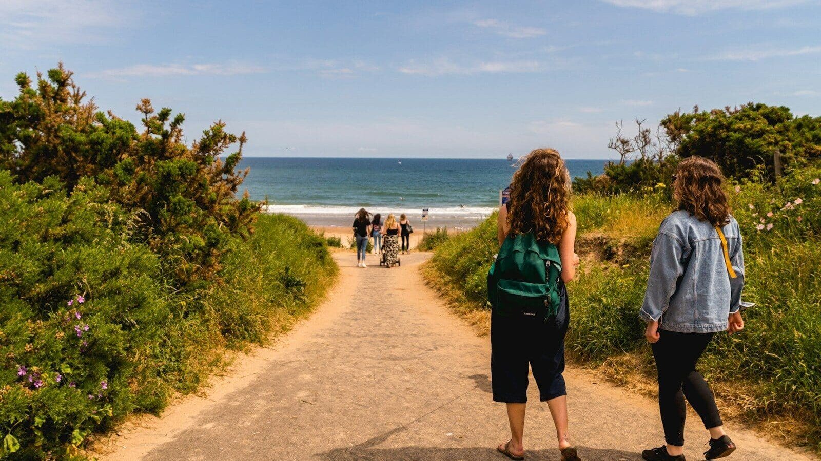 woman in blue long sleeve dress walking on brown sand beach during daytime