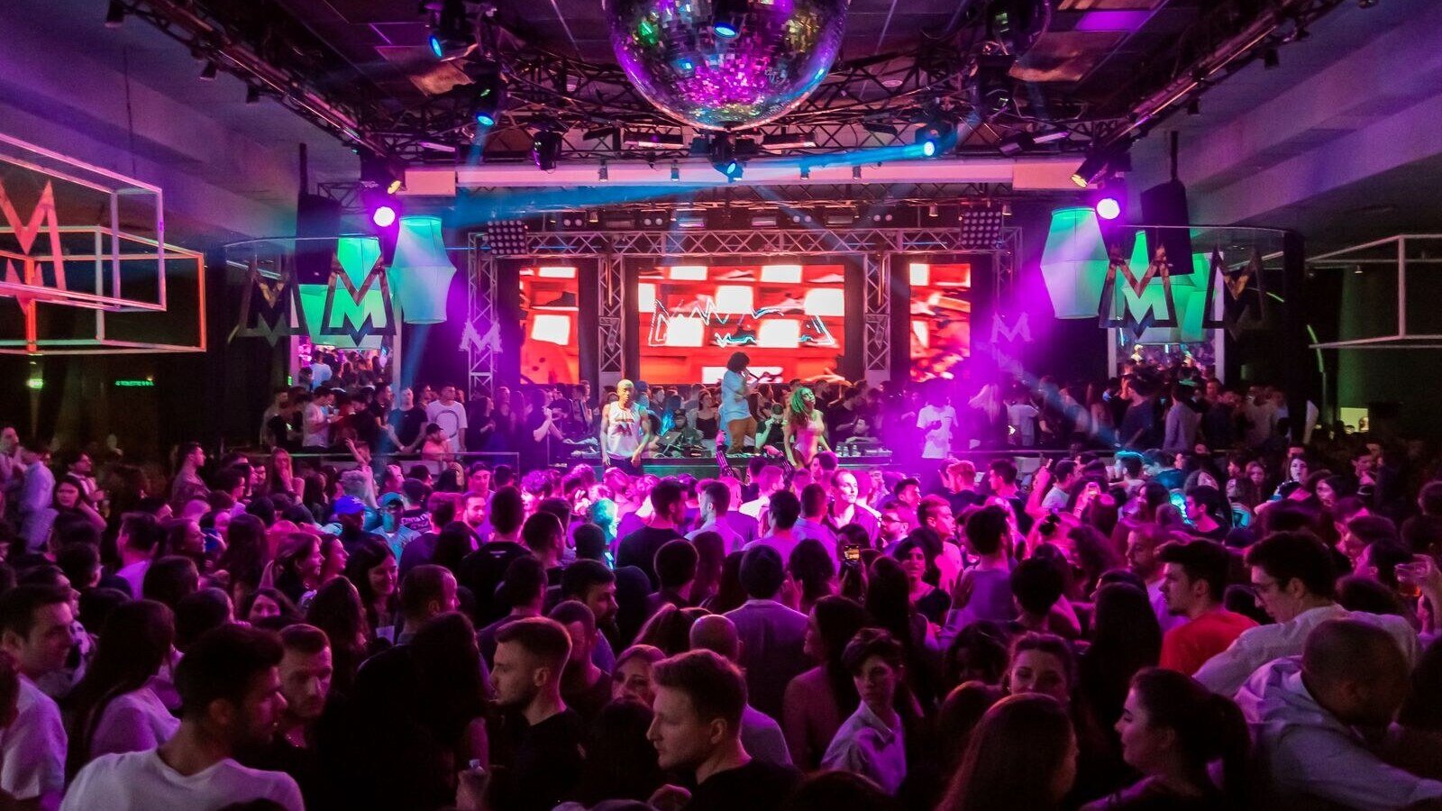 Dynamic crowd at a lively nightclub in Mantua, Italy, with vibrant lights and energetic atmosphere.