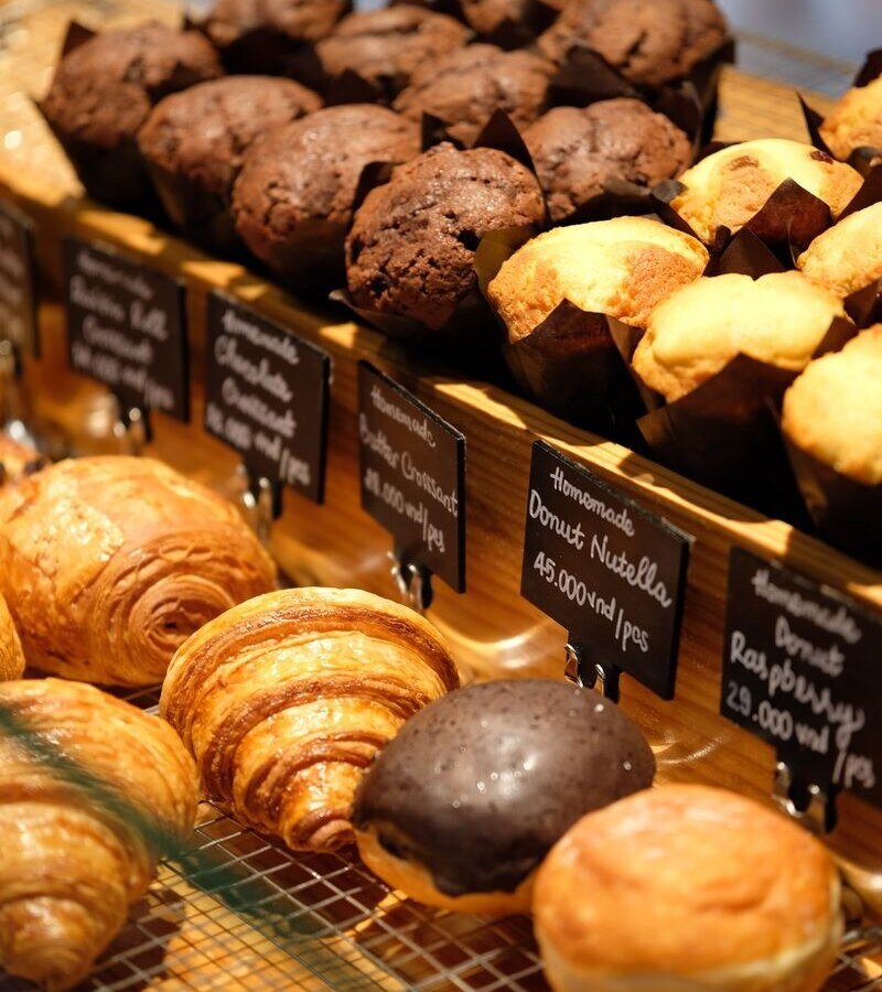 A tempting array of muffins and croissants displayed in a bakery. Perfect for breakfast lovers.