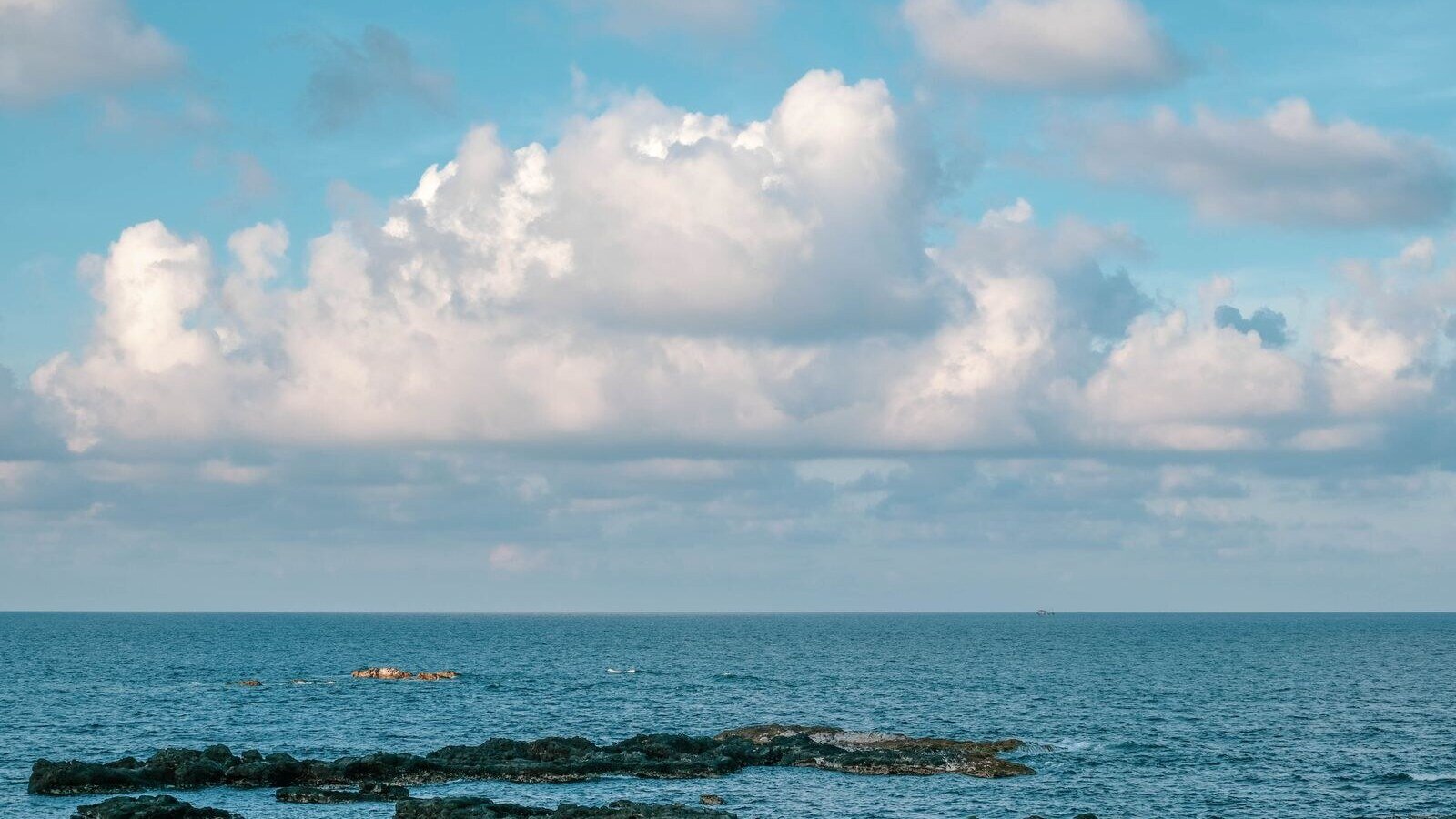 Peaceful coastal scene featuring rocks and sea under a bright blue sky in Bình Thuận, Vietnam.
