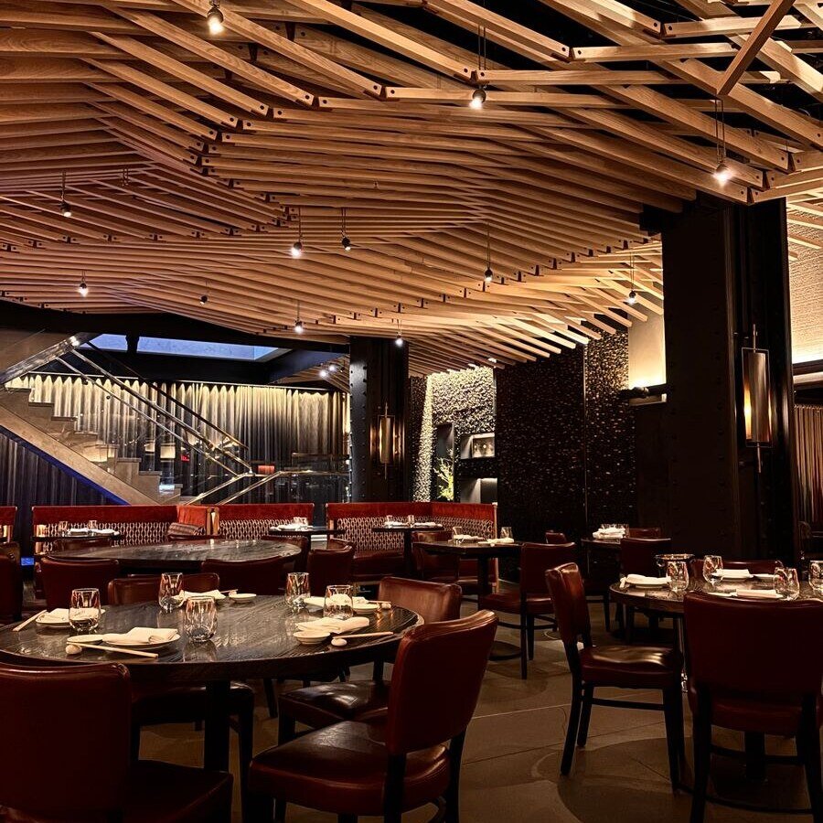 Elegant restaurant interior featuring wooden ceiling and red leather seating.