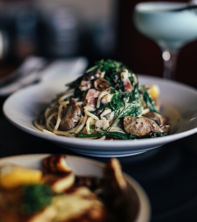 Close-up of a gourmet spaghetti dish with cream sauce, spinach, and mushrooms, perfect for a dinner setting.