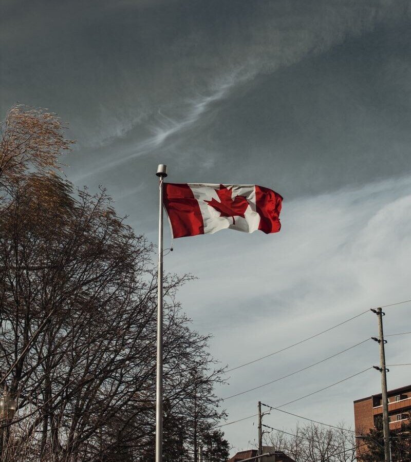 Low angle view of the Canadian flag waving near homes in Milton, Ontario.